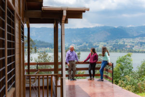 Familia conversando en balcón de cabaña campestre con vista al lago sochagota