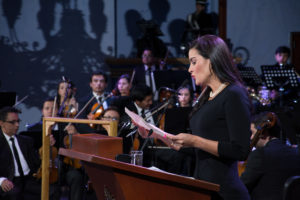 Presentadora dando inicio al evento concierto por la paz, de fondo la opera