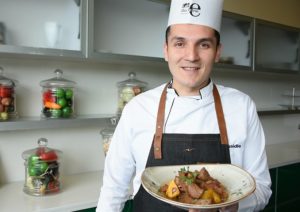 Chef Colombiano uniformado mostrandonos un lomo salteado que preparo