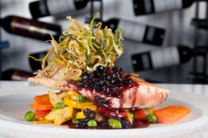 Pescado salteado con ensalada de frutas dulces y cebolla frita decorativa