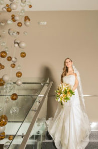 Mujer vestida de novia posando al lado de imponente lampara.