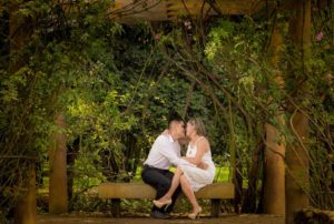 Pareja de esposos sentados, abrazándose en una silla en medio de un bosque.