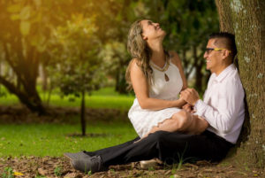 Pareja de novios, riendo, recargados en un árbol, dentro de un bosque