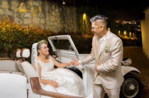 Hombre dandole la mano a su futura esposa en el dia de su boda, para que ella baje del carro antiguo.