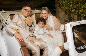 Familia mostrando su anillo de bodas en carro antiguo.