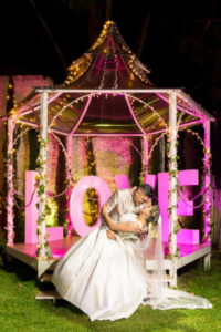 Pareja de esposos recién casados en casa decorativa, con la palabra love de fondo.