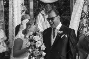 Pareja de recién casados mirándose felices después de que el padre les dio la bendición, mientras cae arroz en augurio de buenos deseos.