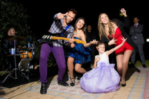 Guitarrista posando para fotografía con invitadas a fiesta y dama de honor.