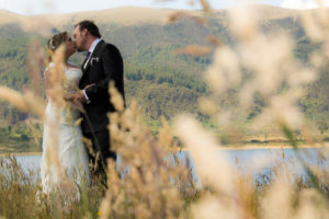 PAreja besandose en medio de las ramas y de un hermoso lago de fondo.