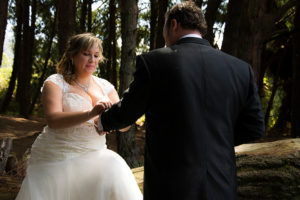 Mujes vestida de novia colocandole el anillo a su futuro esposo en boda campestre.