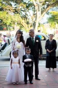 La novia entra a la iglesia acompañada de su padre y los pajecillos en un día soleado.