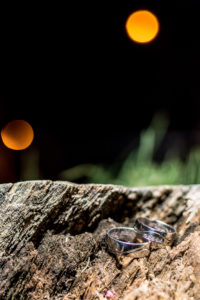 Anillos de compromiso y de bodas en un trozo de madera con el reflejo de la noche.