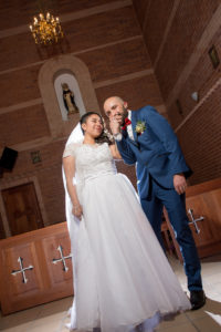 Hombre besando la mano de su pareja, felices en la iglesia después de casarse.