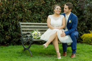 Pareja de esposos sentados en una silla en su boda civil al aire libre.