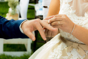 Manos colocándose el anillo de bodas.